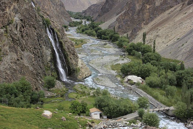 Manthokha Waterfall cascading down rocky cliffs into a green valley stream near Skardu, Gilgit-Baltistan, Pakistan.