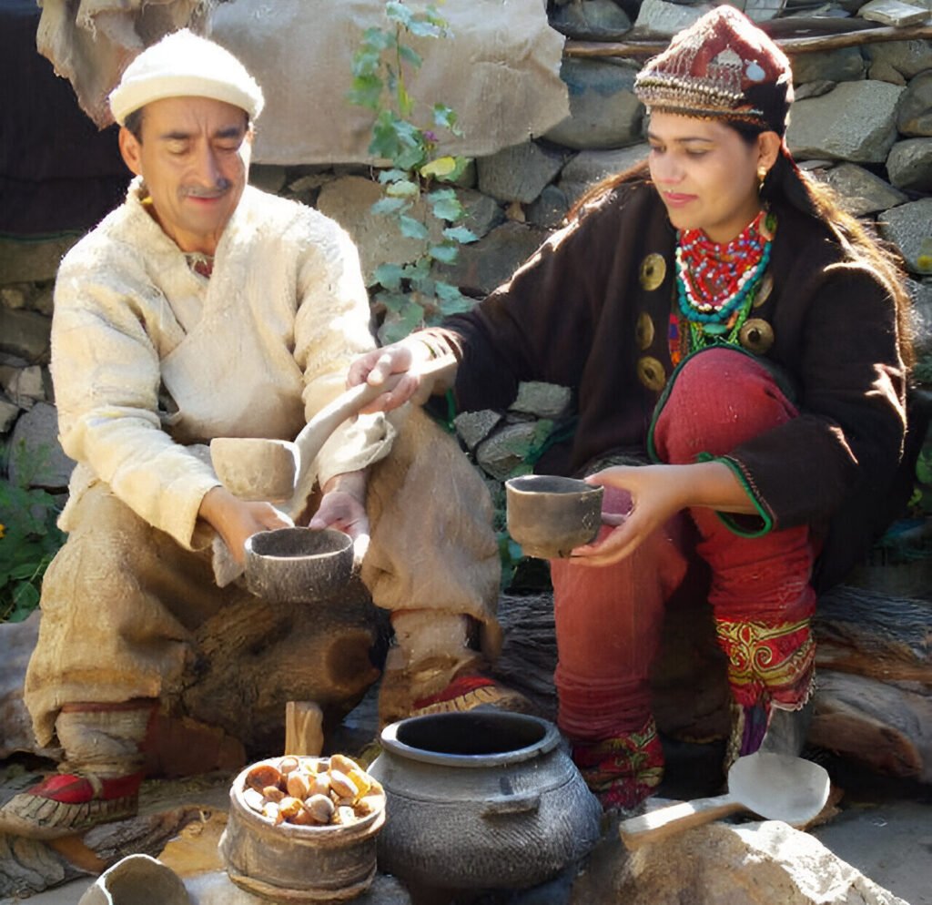 A Balti couple in traditional attire sitting by ethnic stone and copper cooking pots in Gilgit-Baltistan, Pakistan.
