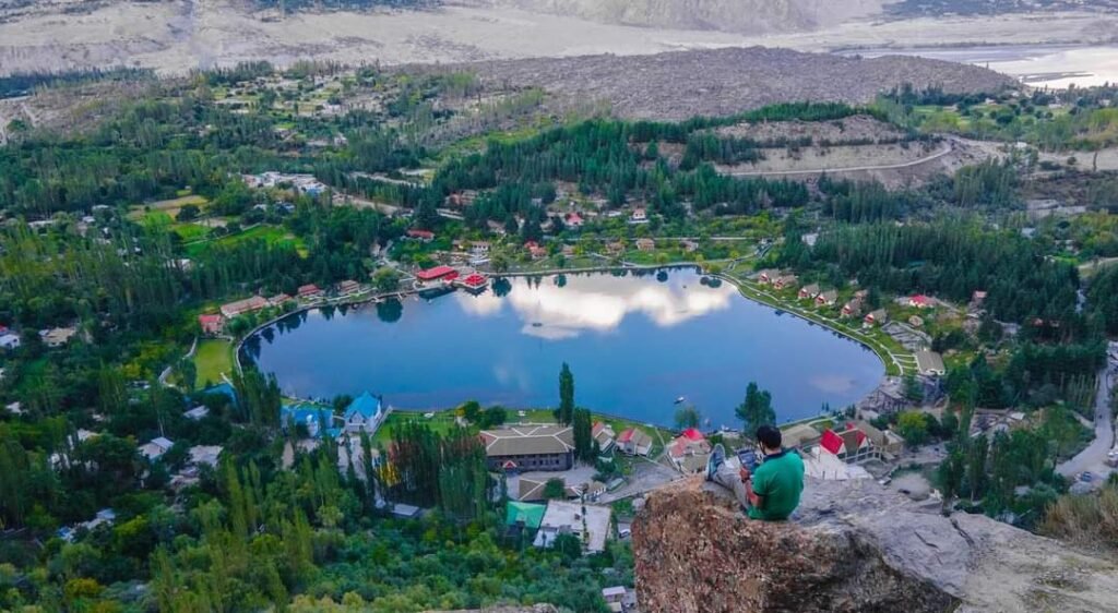 Aerial view of the heart-shaped Shangrila Lake (Lower Kachura Lake) and red-roofed resort cottages surrounded by green trees and mountains in Skardu, Gilgit-Baltistan, Pakistan.