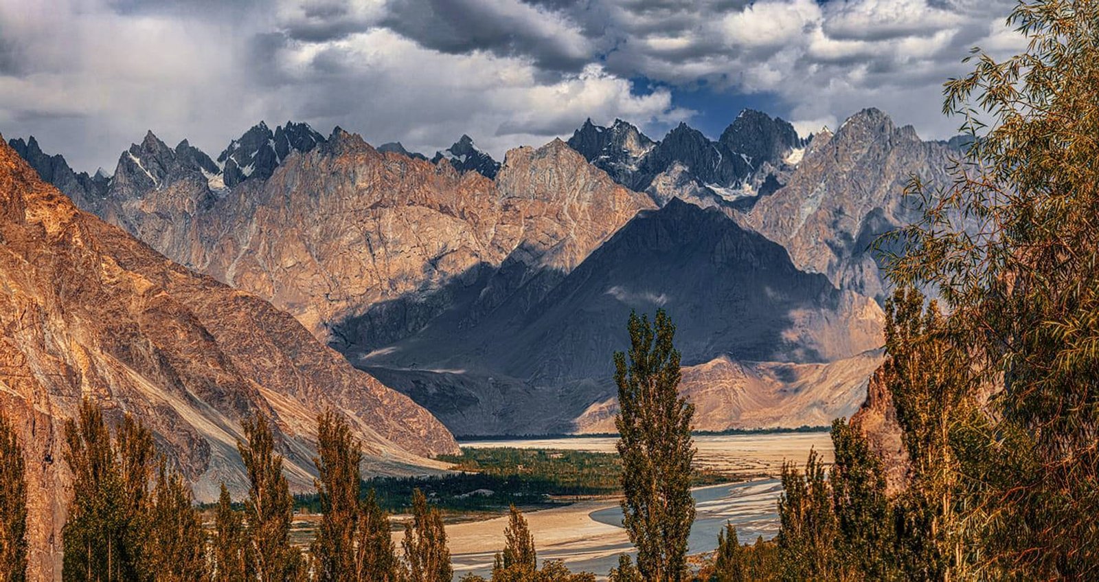 The sharp, jagged peaks of the Passu Cones tower over the Hunza River valley in Gilgit-Baltistan, Pakistan, showcasing the rugged beauty of Northern Discover tours.