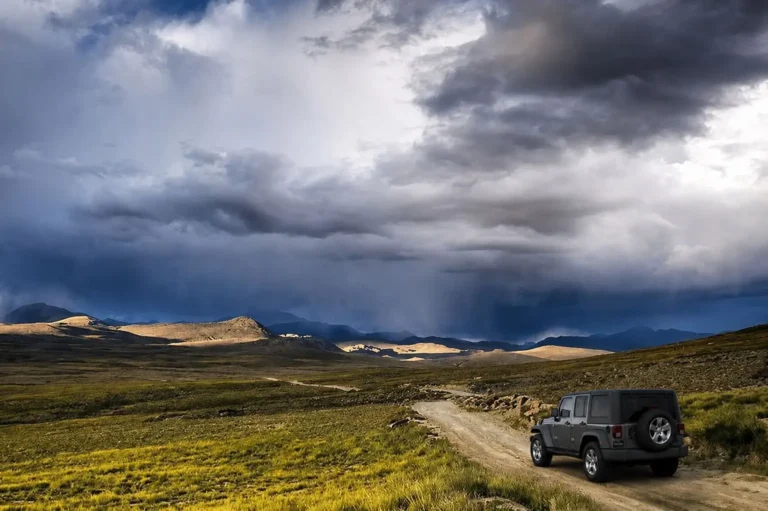 Deosai Jeep Safari Tour from Skardu. A 4x4 safari jeep driving along a dirt trail across the alpine plateau in Deosai National Park.