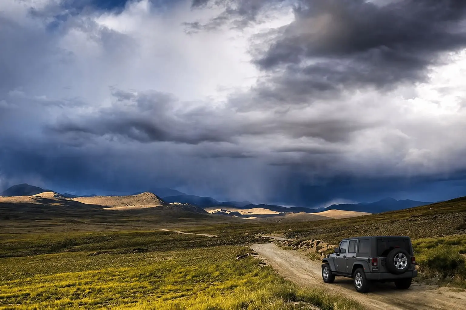 Deosai Jeep Safari Tour from Skardu. A 4x4 safari jeep driving along a dirt trail across the alpine plateau in Deosai National Park.