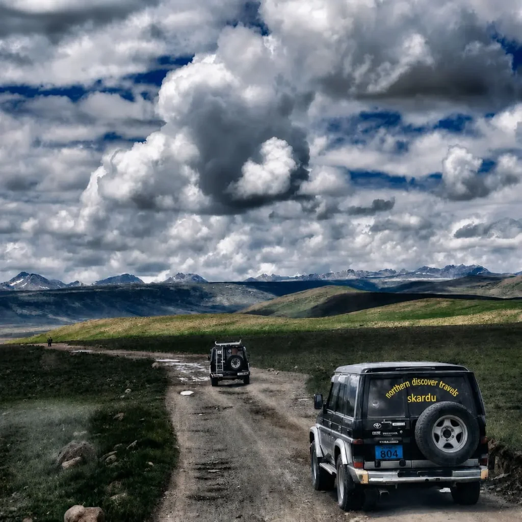 Skardu to Deosai distance route with a 4x4 jeep driving across the Deosai Plains under dramatic clouds on the way from Skardu.