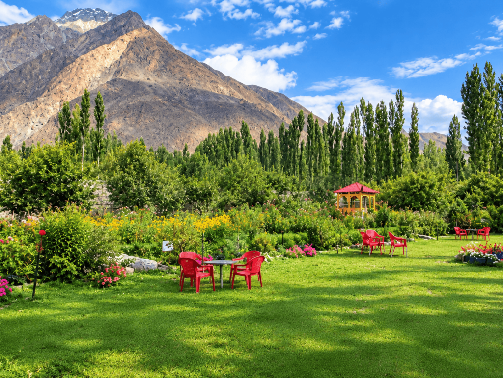 Hashupi Bagh in Gilgit-Baltistan with colorful flower gardens, tall trees, and mountain views