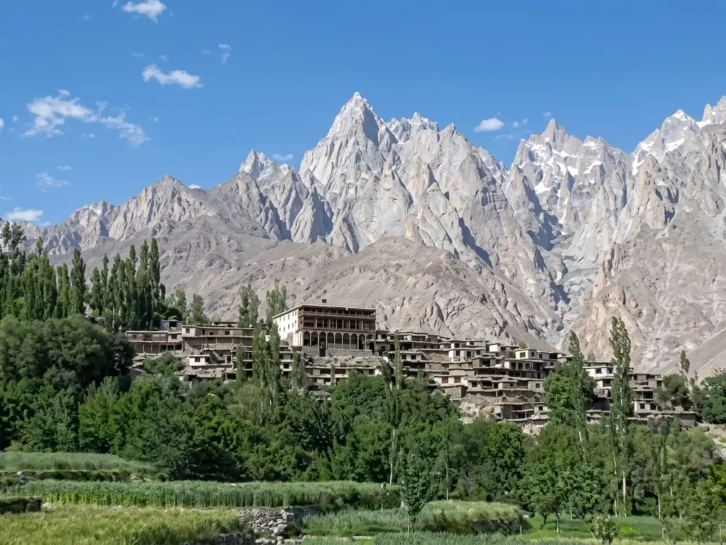 Traditional stone houses and historic fort-style architecture of Machulu village surrounded by green fields and towering rocky peaks in Ghanche, Gilgit-Baltistan.